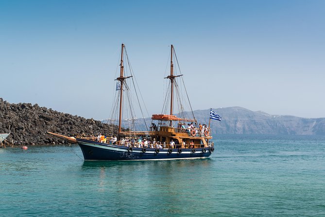 A cruise boat on the water below the volcanic cliffs of the Santorini caldera